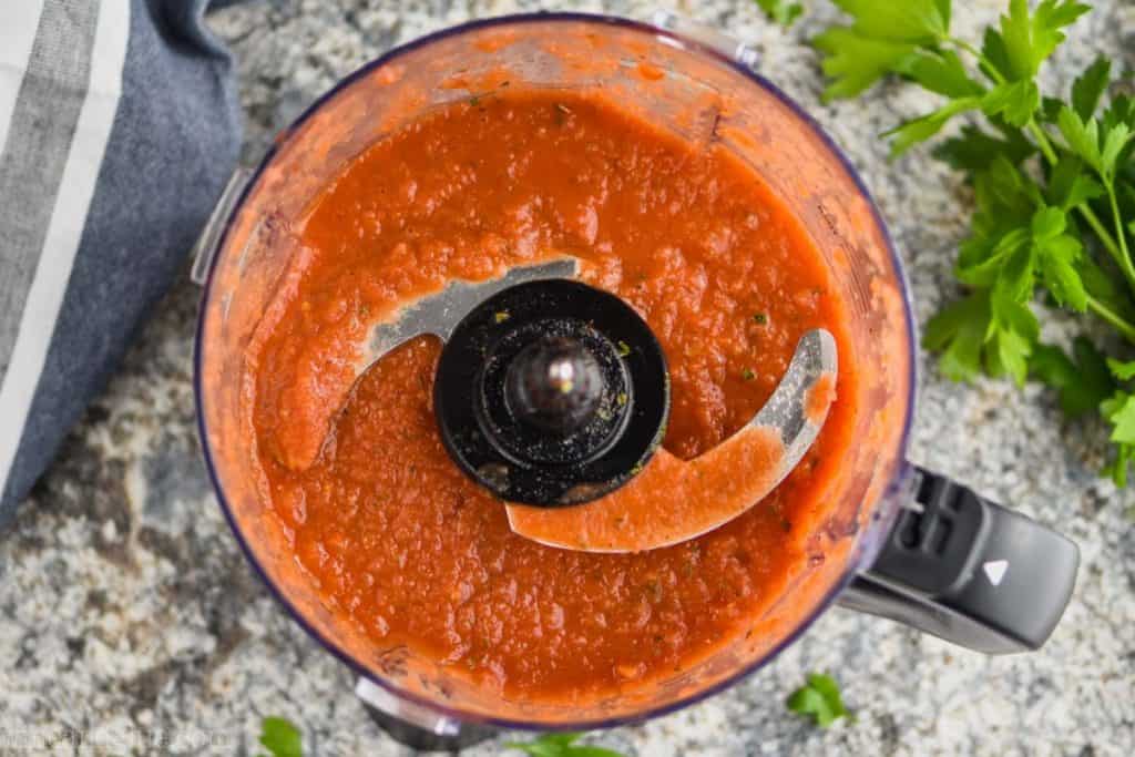 over head view of a food processor filled with pizza sauce from scratch