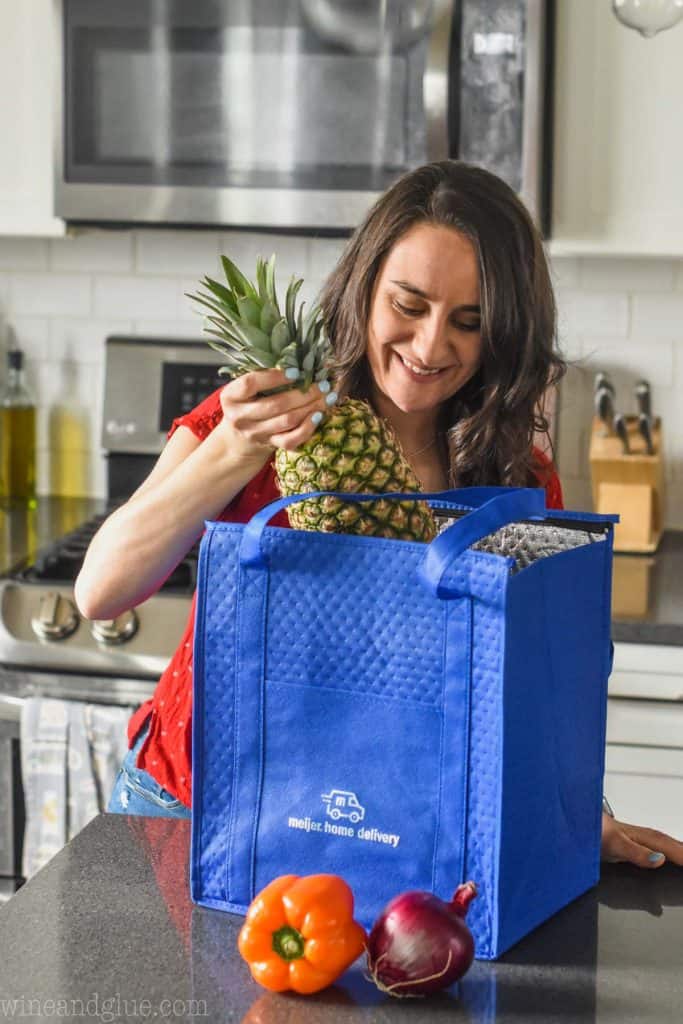 woman pulling a pineapple out of a meijer home delivery bag