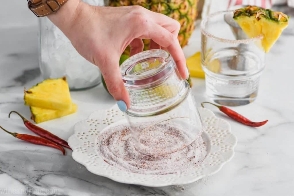 woman dipping a glass in a sugar salt mixture to rim a margarita glass
