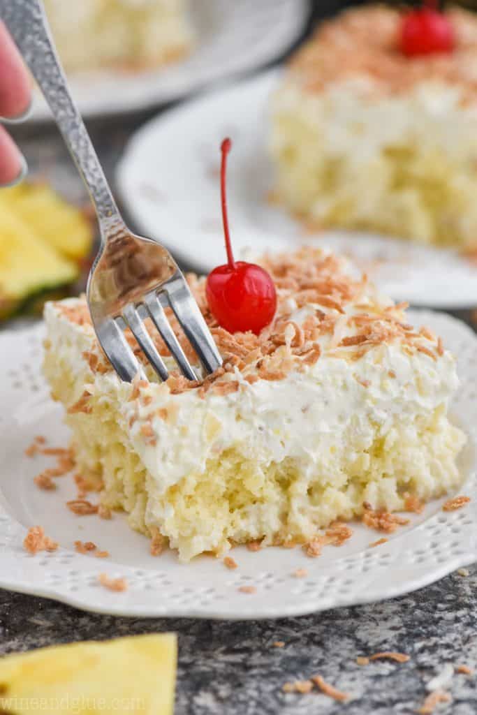fork digging into a piece of pina colada poke cake