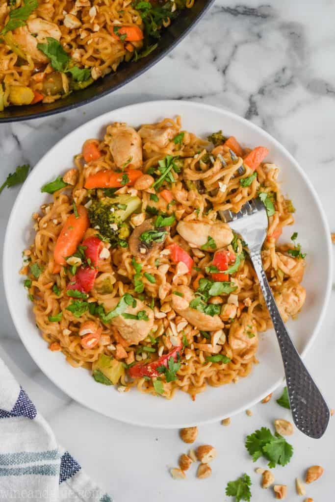 peanut butter stir fry noodles on a white dish with a fork twisting the noodles