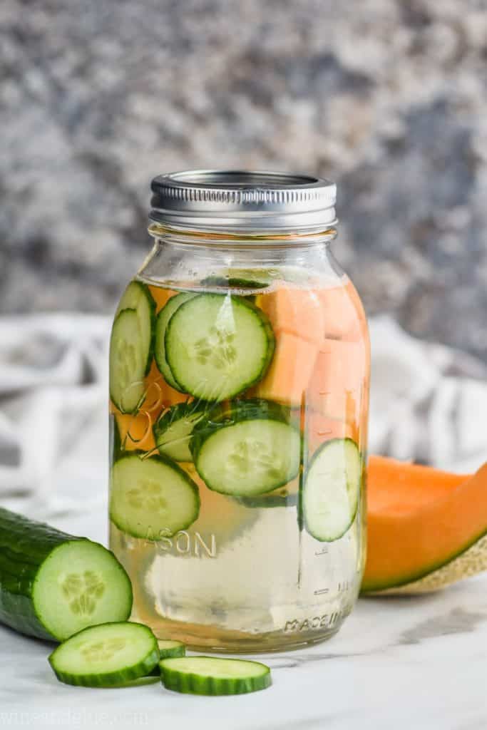 sliced cucumber and cubed melon in a mason jar filled with water to make a great infused water recipe