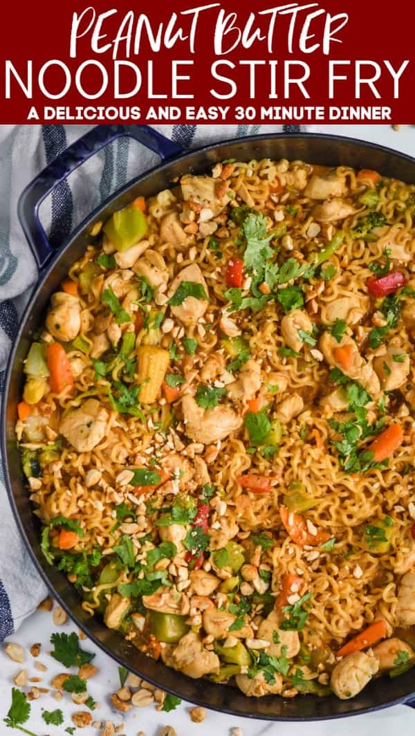 overhead view of peanut butter stir fry noodles in a large skillet, topped with fresh cilantro and chopped peanuts