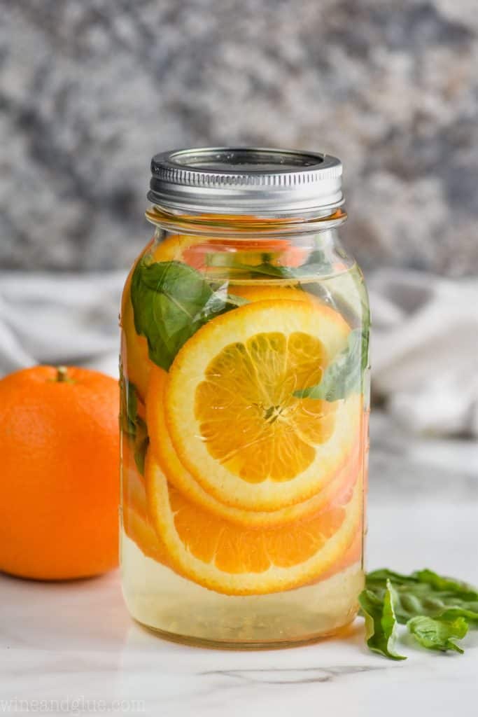 sliced oranges in a mason jar filled with water and fresh basil leaves to make orange basil infused water
