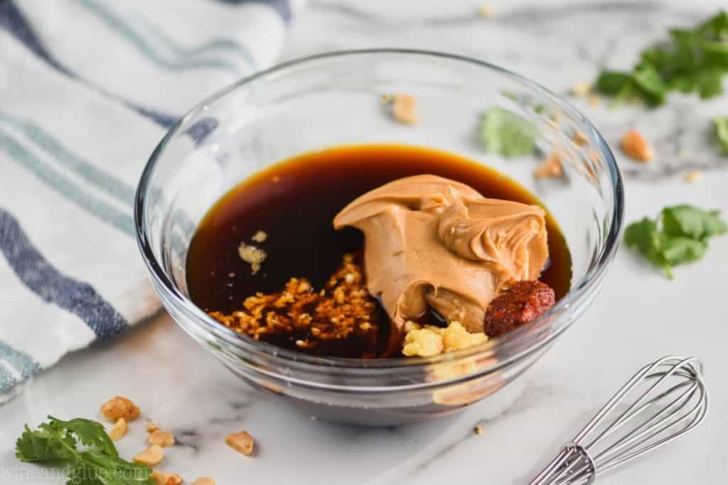 a bowl filled with ingredients for peanut sauce that have not been whisked together yet