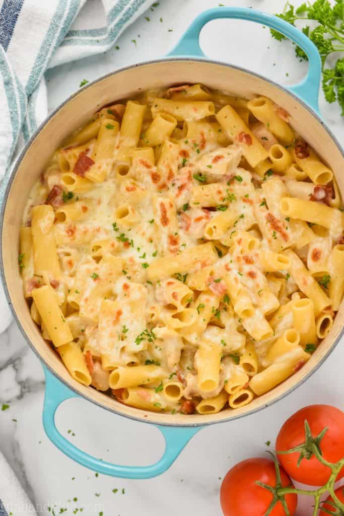 overhead view of chicken bacon ranch pasta bake with broiled mozzarella and rigatoni in a teal dutch oven