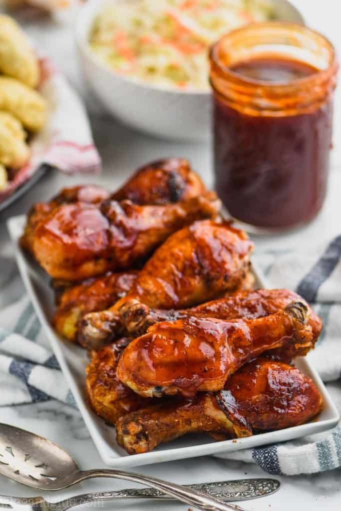 rectangular white plate piled with chicken drumsticks covered in easy homemade bbq sauce recipe