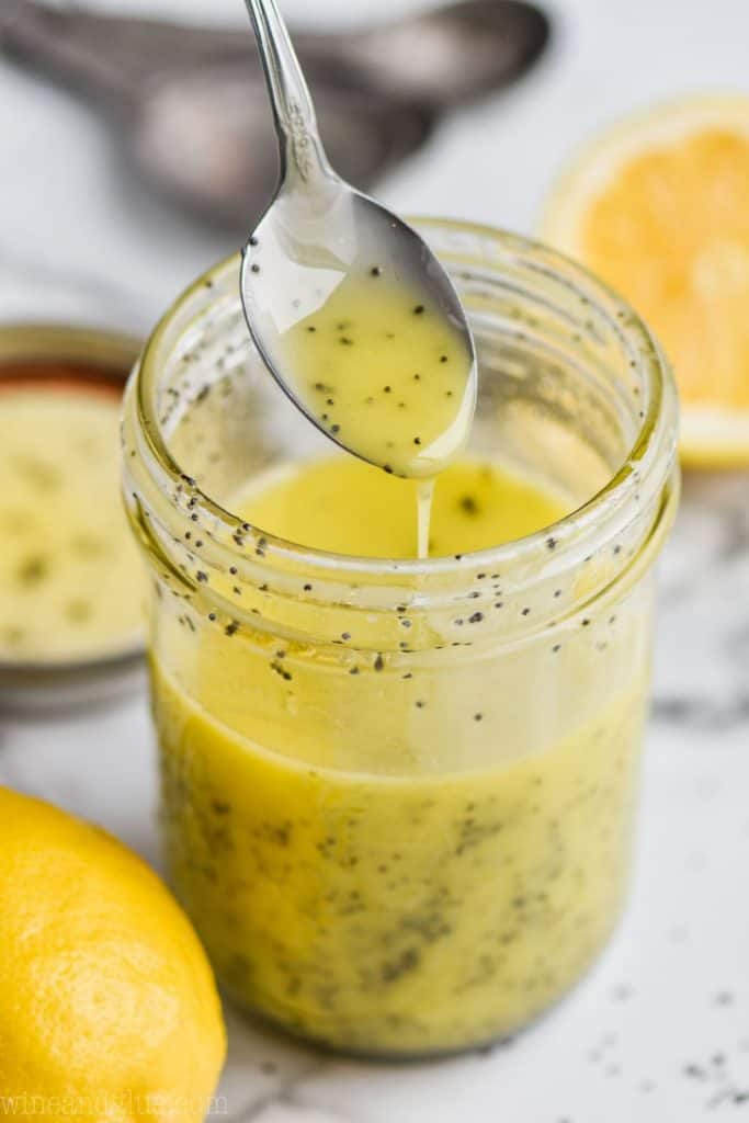 teaspoon dripping out a small amount of lemon poppy seed dressing back into a mason jar