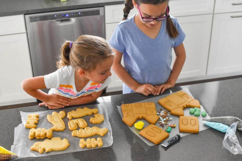 two little girls standing at a counter with supplies to decorate cookies