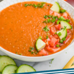pinterest graphic of bowl of gazpacho soup with pieces of cucumber, tomato, and parsley on top, says: "gazpacho soup simplejoy.com"