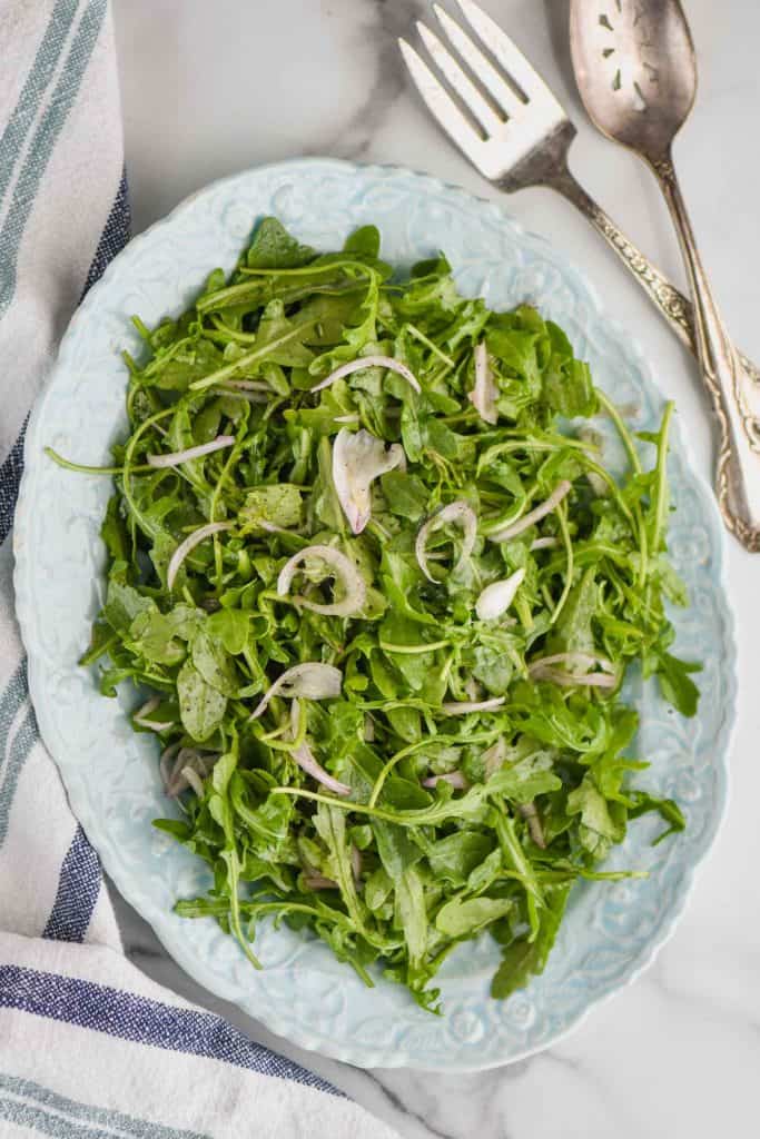 overhead view of an oval plate with an arugula salad on it 