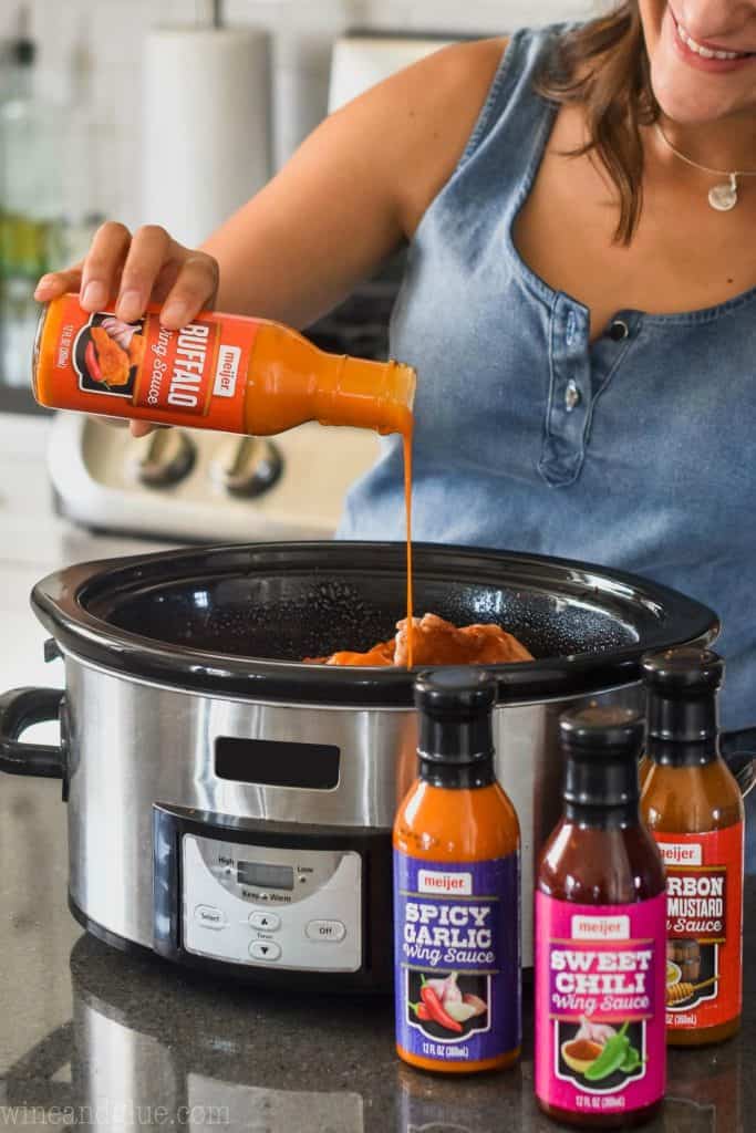 woman pouring wing sauce into crock pot to make crock pot chicken wings