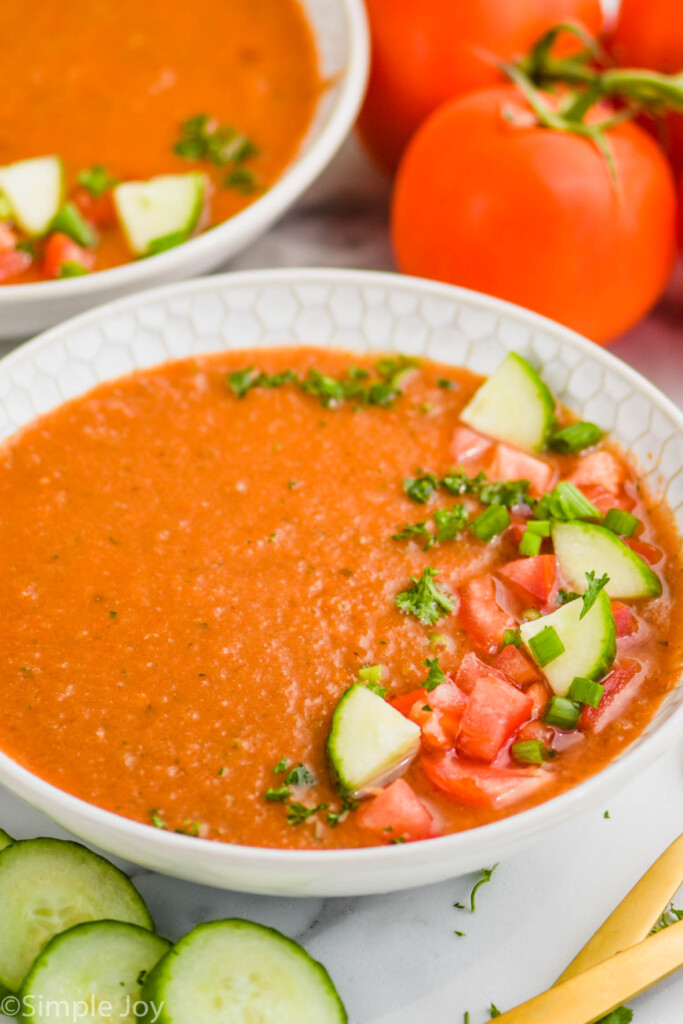 bowl of gazpacho soup with pieces of cucumber, tomato, and parsley on top