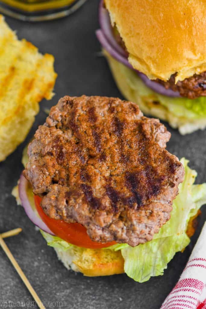 overhead of a hamburger patty made with hamburger patty seasoning, the top of the bun off and grill makes visible on the patty