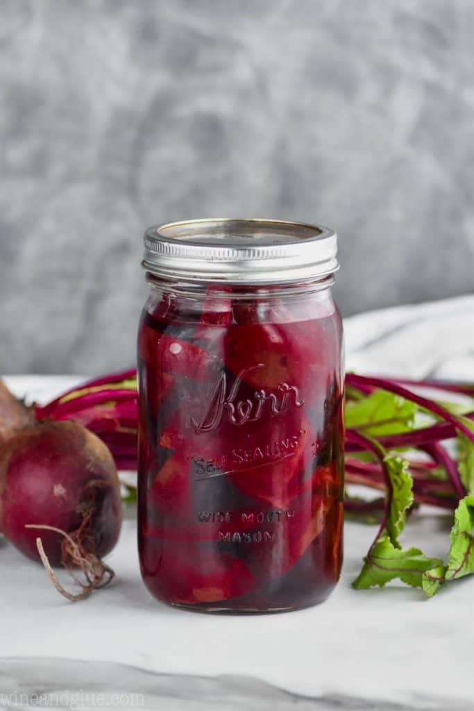 mason jar on a white surface against a gray background filled with pickled beets recipe