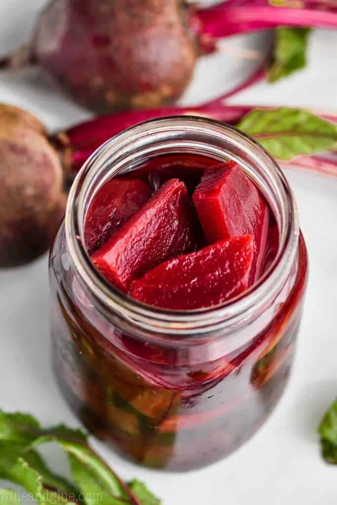 overhead view of a mason jar with pickled beets in it and raw beets laying next to it