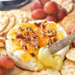 pinterest graphic brie cheese topped with marmalade, honey, and pecans being pulled out with a knife says: the best baked brie recipe simplejoy.com