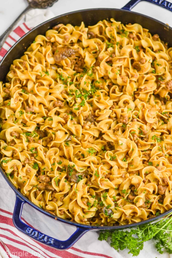 overhead view of ground beef stroganoff recipe in a large navy blue skillet on a white surface