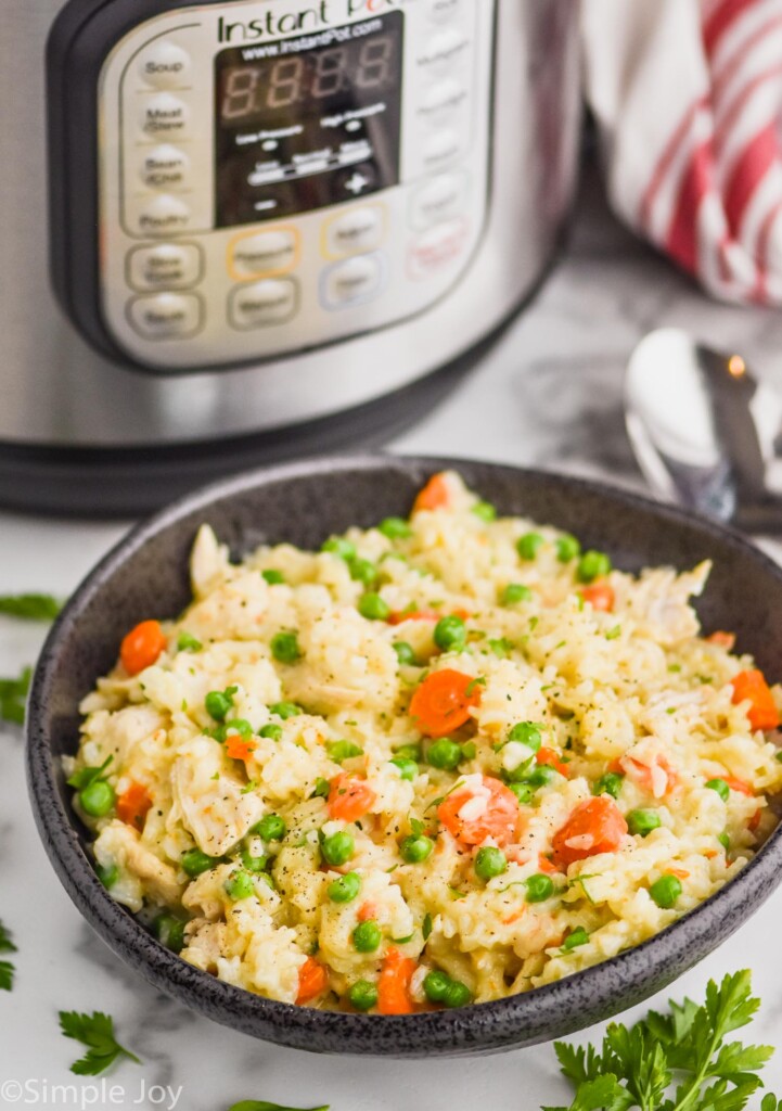 black bowl filled with instant pot chicken and rice casserole in front of an instant pot