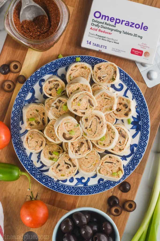 mexican tortilla roll up recipe pilled up on a blue and white patterned plate on top of a cutting board