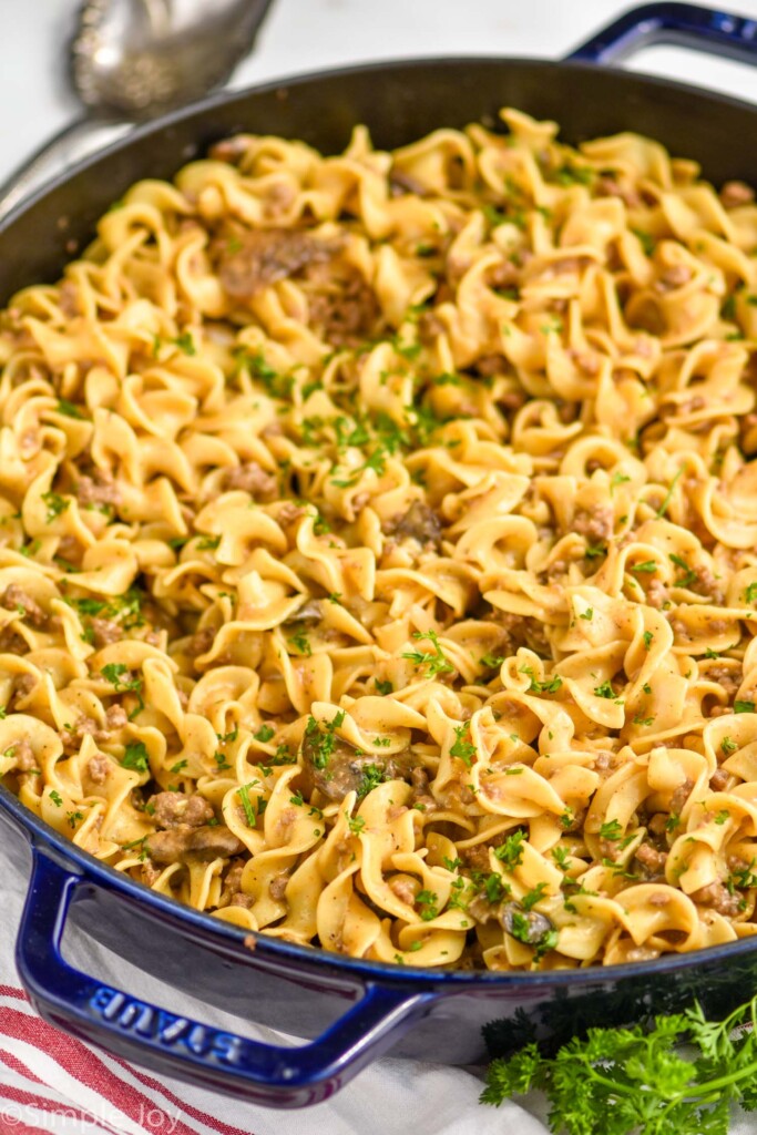 a large skillet full of ground beef stroganoff recipe garnished with minced parsley