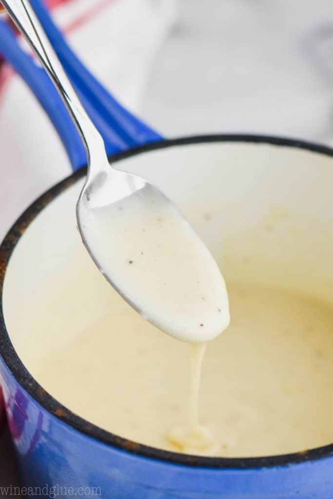 up close of spoon dripping condensed cream of chicken soup into a blue sauce pan
