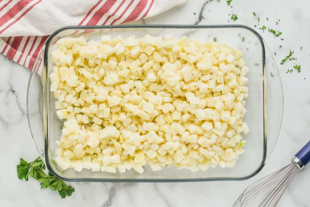 landscape photo of a baking dish filled with square frozen hash brown potatoes on a white surface to make cheesy potato casserole