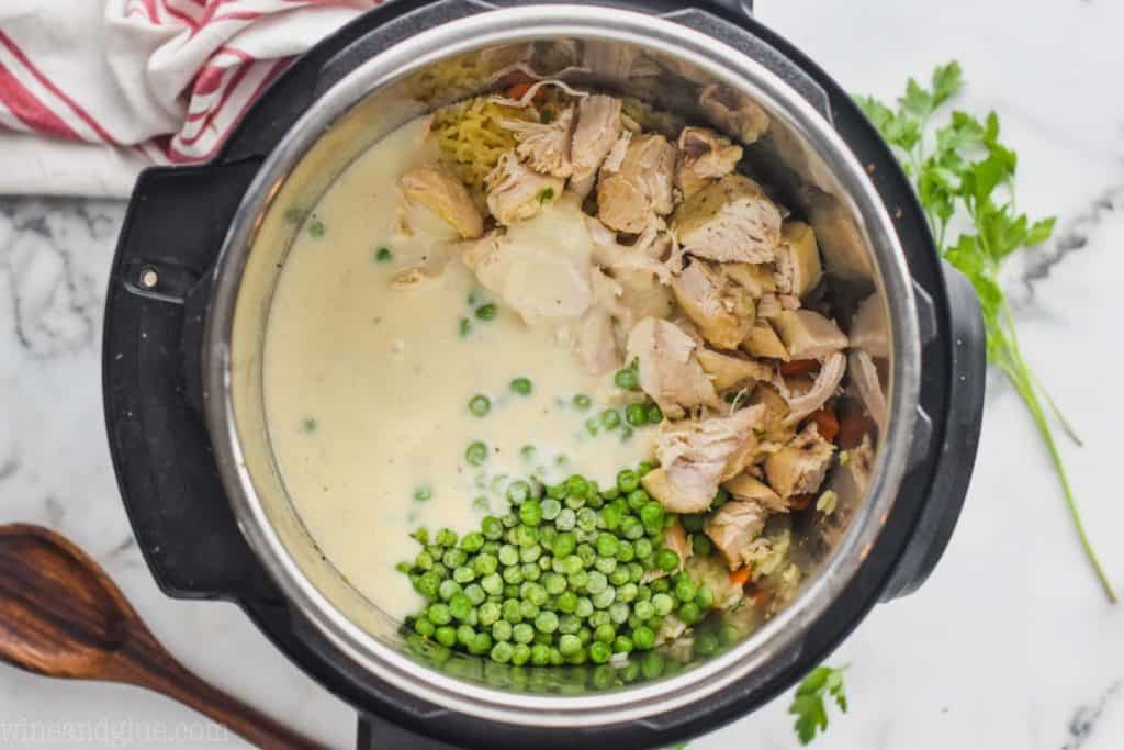 overhead view of a pressure cooker filled with homemade condensed cream of chicken soup frozen peas and cooked chicken to make instant pot chicken and rice
