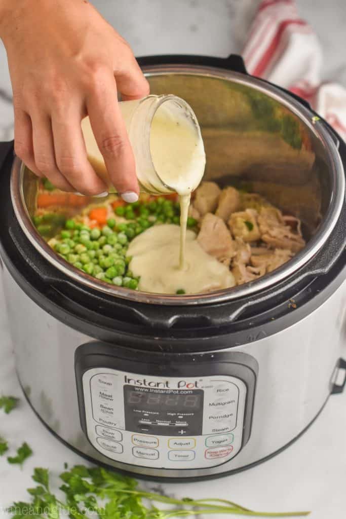 hand pouring homemade condensed cream of chicken soup into an instant pot that has cooked instant pot chicken breast and rice