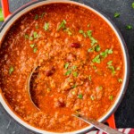 overhead view of a red stock pot with a vegetarian chili recipe and a metal ladle coming out of it