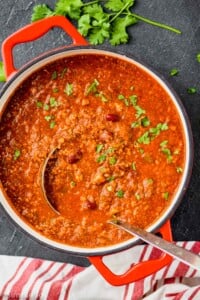 overhead view of a red stock pot with a vegetarian chili recipe and a metal ladle coming out of it