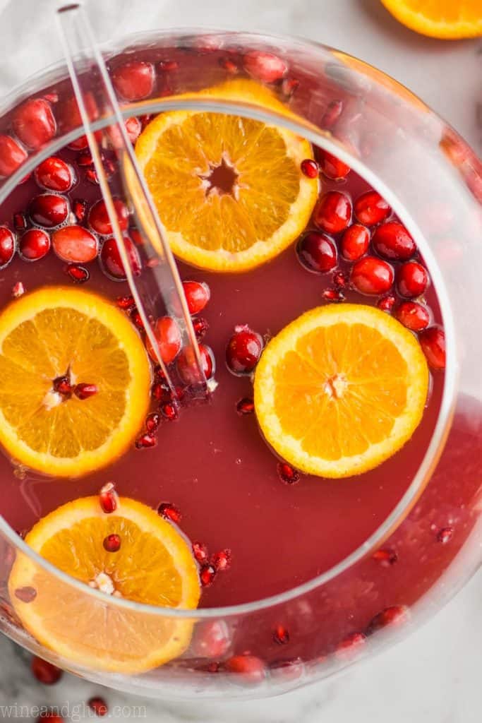 overhead view of a sphere punch bowl full of christmas punch with orange slices and cranberries floating in it