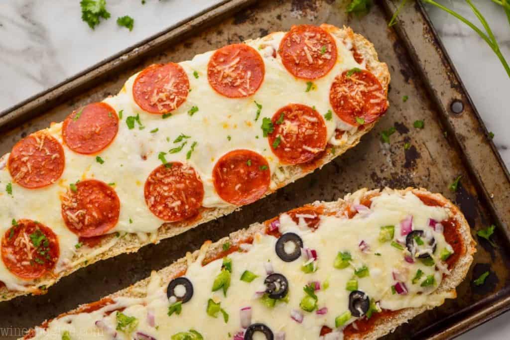 overhead view of two halves of french bread pizza on an old metal tray
