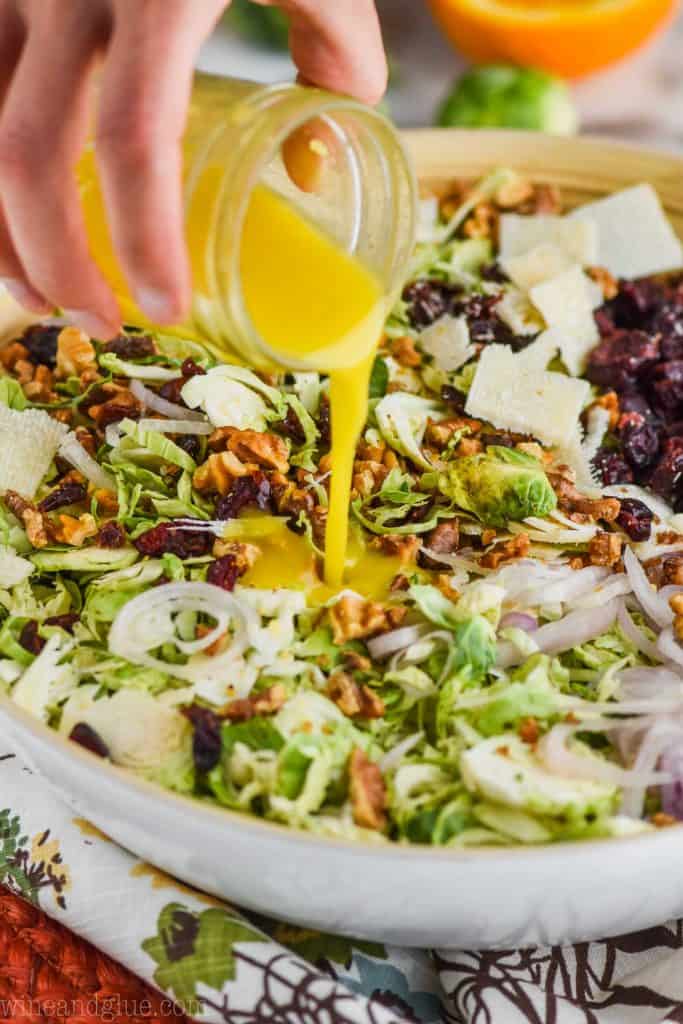 citrus salad dressing being poured into healthy brussels sprout salad recipe