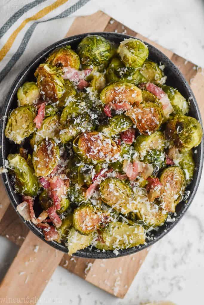 overhead view of a black bowl on a cutting board filled with roasted brussels sprouts with bacon