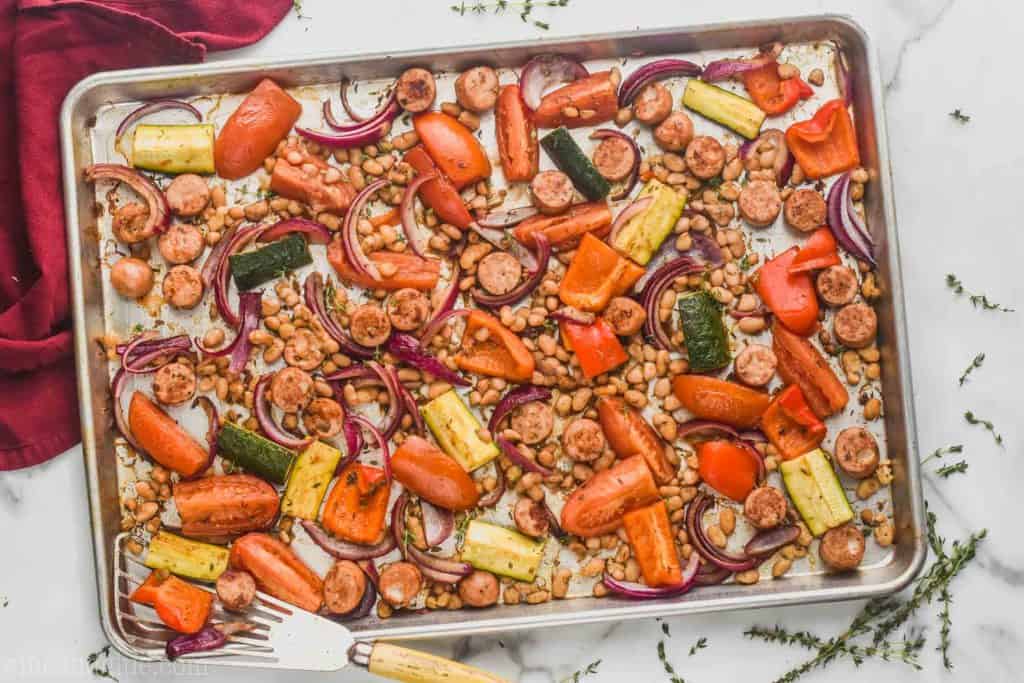 overhead view of sausage and vegetable sheet pan dinner on a rimmed baking sheet after roasting 
