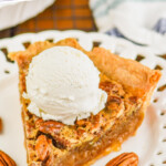 Pinterest graphic of a piece of the best pecan pie on a fancy white plate with a large scoop of vanilla ice cream on top and the rest of the pie blurred in the background, says: the best pecan pie recipe simplejoy.com