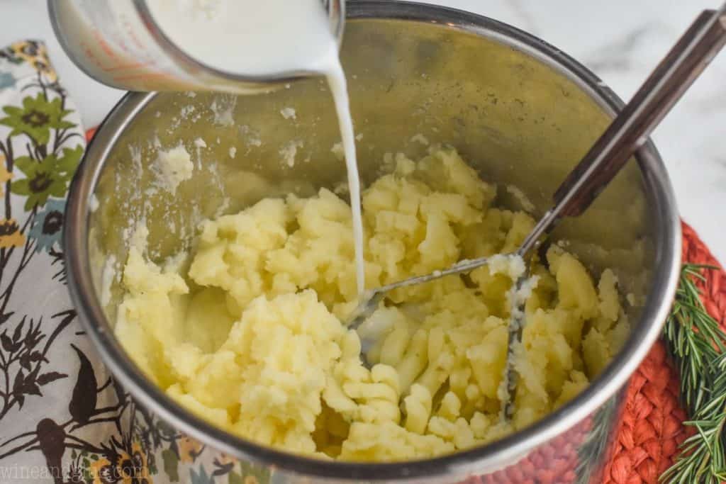 milk being poured into the bowl of an instant pot that has instant pot mashed potatoes in it