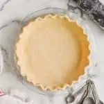 a pie crust recipe that has been transferred to a glass pie pan and the rim of it has been pinched