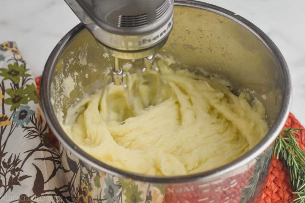 mashed potatoes that are being blended with a hand mixer in an instant pot