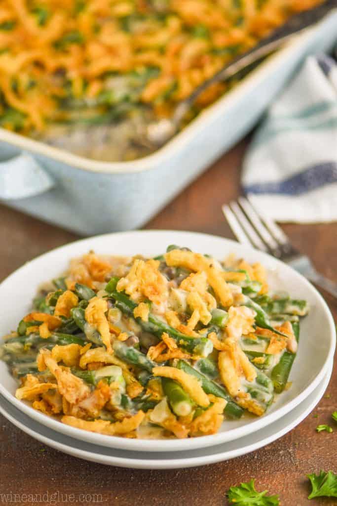 fresh green bean casserole on a small white plates with casserole in the background