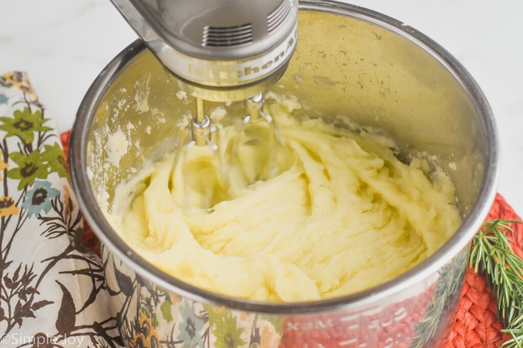 mashed potatoes that are being blended with a hand mixer in an instant pot