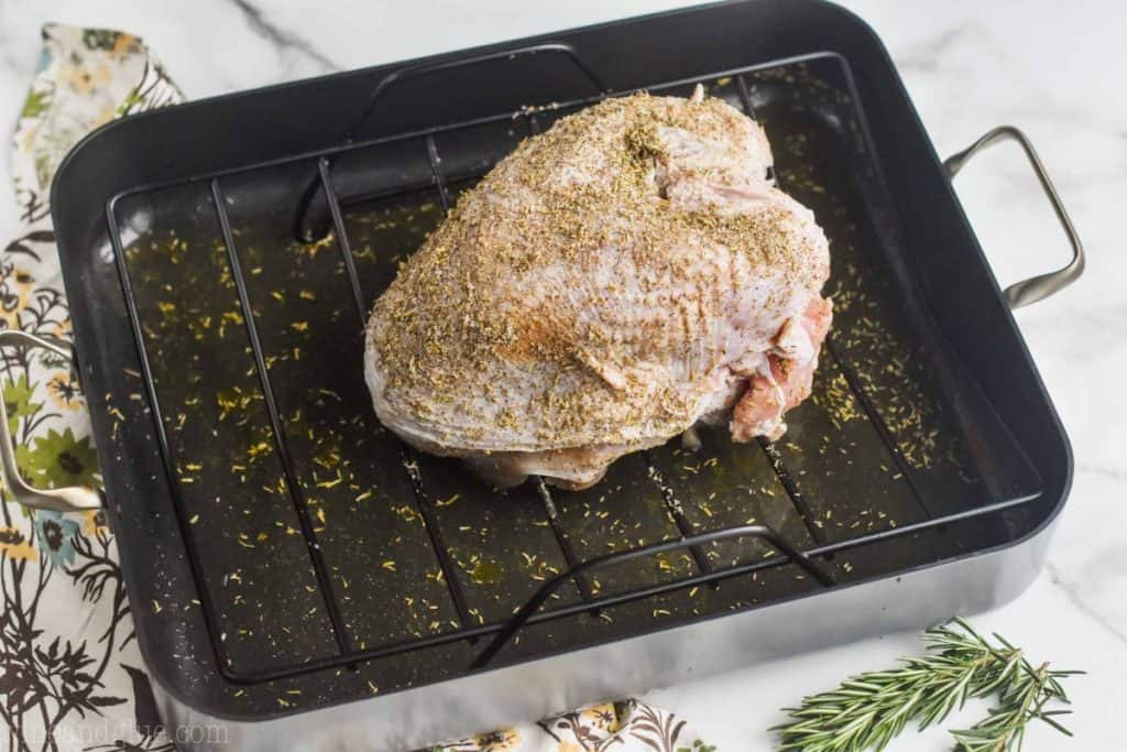 a raw turkey breast that has been brined and has a rub on it sitting on a wire rack in a roasting pan