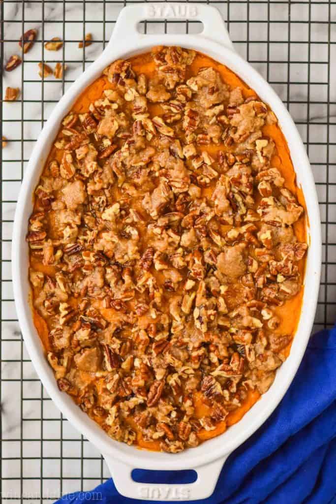 overhead view of a sweet potato casserole recipe topped with pecans and brown sugar in a white oval casserole dish