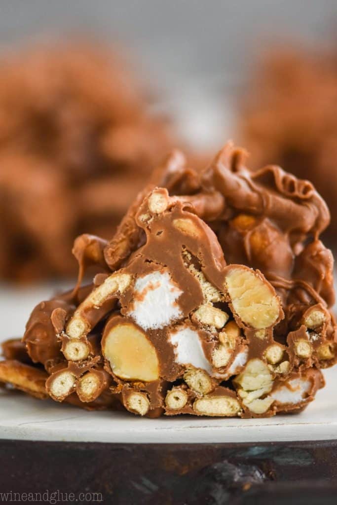 a close up picture of a chocolate haystack cookie that has been cut in half to show chow mien noodles, peanuts, and marshmallows