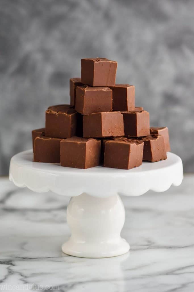 a four level high pyramid of easy fudge on a small white cake stand against a gray background