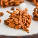 close up of a haystack cookie with peanuts, marshmallows, and chocolate chips blurred in the background