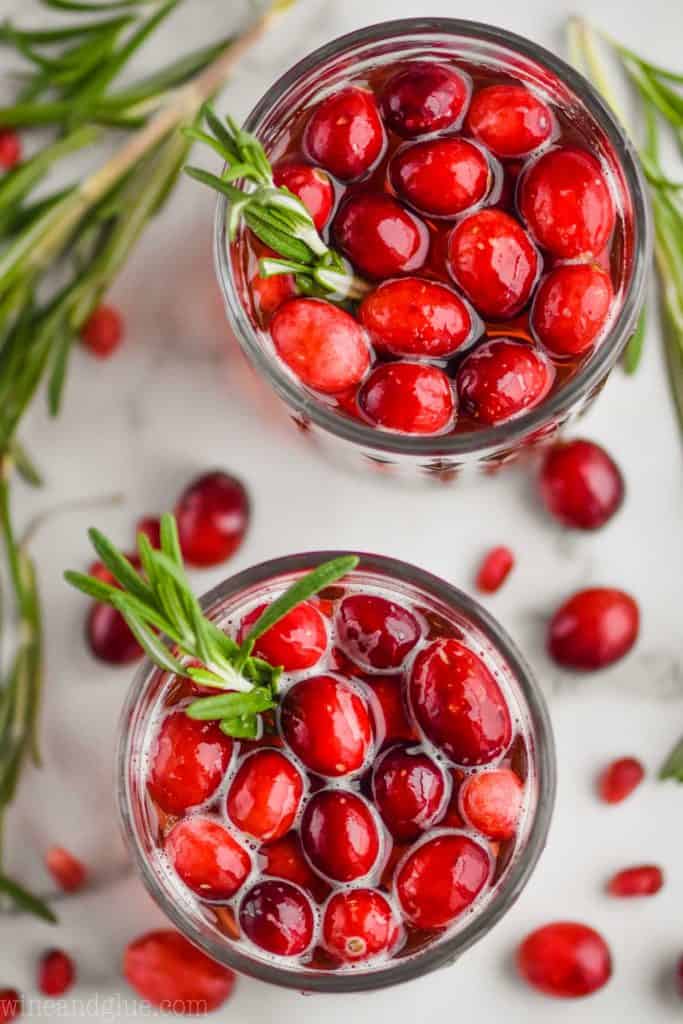 overhead view of two glasses full of red sangria with fresh cranberries and sprigs of rosemary in them