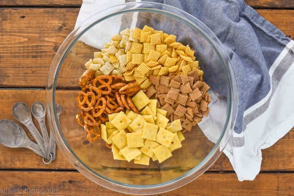 overhead view of a clear mixing bowl with dry ingredients for chex mix