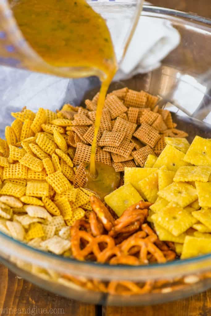 up close of dry ingredients for ranch chex mix recipe with the liquid ingredients being poured over it